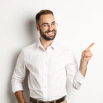 Selbstbewuster businessman sieht gluecklich aus zeigt mit dem finger links