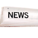 Rolled up newspaper with news headline set against a white background